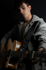 Obraz premium Shirtless young man in denim jacket playing guitar in photo studio