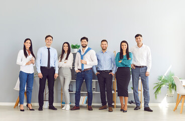 Obraz premium Full length portrait of business people men and women looking at camera and smiling indoors. Company employees team or group of staff standing in office confidently. Business people portrait.