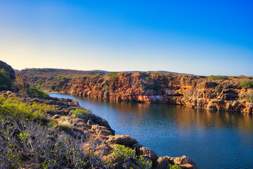 The gorge of the Yardie Creek in Cape Range National Park, Western Australia, with red limestone rocks and stunted outback vegetation
