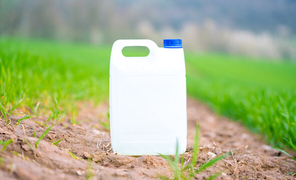 plastic canister with fertilizer pesticide herbicide or fungicide on a green field