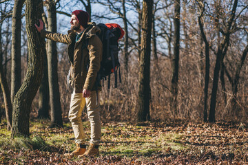 Naklejka premium young hipster man traveling with backpack in spring autumn forest