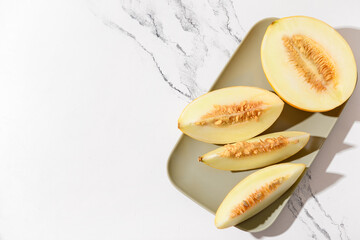 Plate with pieces of sweet melon on white background