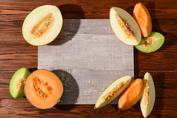 Pieces of sweet melon with board on wooden background