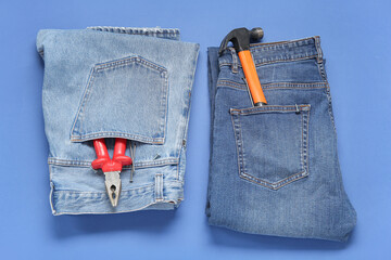 Jeans with different tools in pockets on blue background. Labor Day celebration