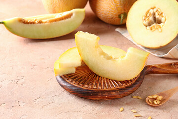 Wooden board with pieces of sweet melon on pink table