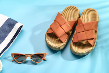 Female stylish flip flops with beach accessories on blue background