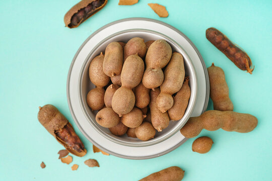 Bowl of tasty tamarinds on blue background