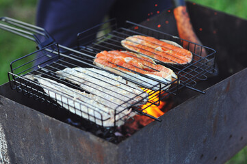Cooking fish. Fish being barbecued on a grill outside. BBQ Food. Fresh fish cooking outdoors on a...