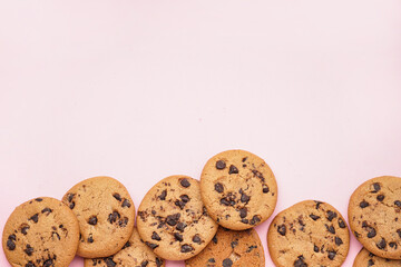 Tasty cookies with chocolate chips on pink background