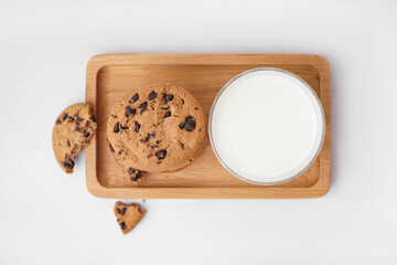 Tasty cookies with chocolate chips and glass of milk on white background