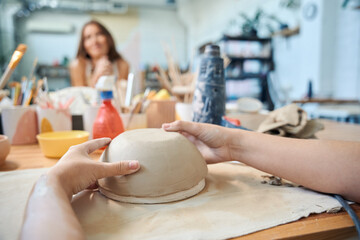 Unrecognizable woman sculpting clay bowl in workshop