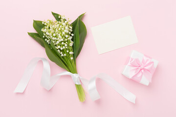 Lilies of the valley with gift box on color background, top view