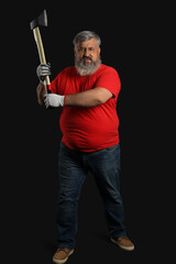Portrait of mature lumberjack swinging axe on black background