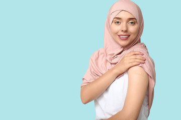 Muslim woman with medical patch on arm against blue background. Vaccination concept