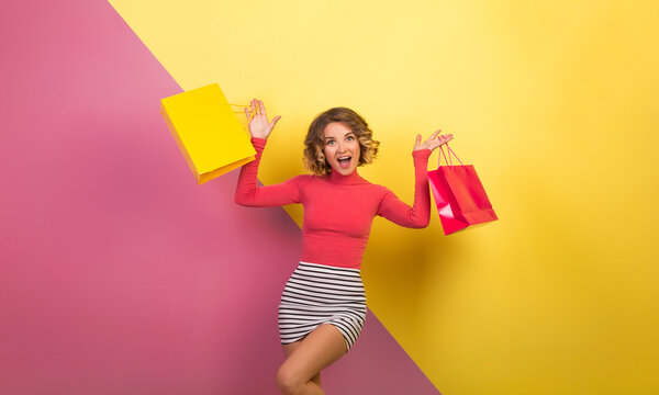 exited attractive woman in stylish colorful outfit holding shopping bags