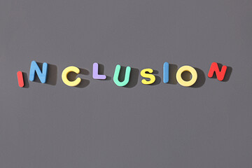 Word INCLUSION made from colorful wooden letters on grey background