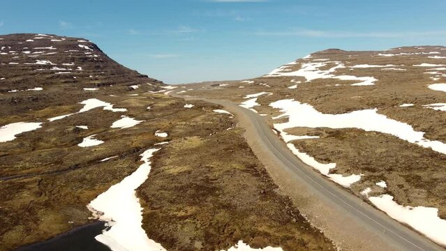 Mountain pass curvy road, high arctic, summer, Iceland, snow, blue sky, bright sunshine. Road trip, emptyness, alone. Polar climate