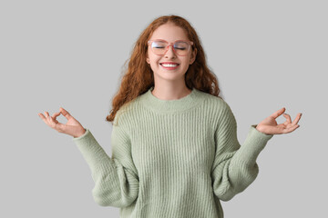 Portrait of relaxed young woman meditating on grey background