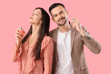 Young couple with bottles of perfume on pink background
