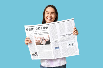 Beautiful young woman with newspaper on blue background