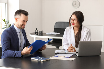 Human resources manager interviewing male applicant at table in office