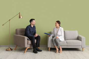 Human resources manager interviewing applicant near green wall in office