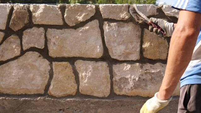 Building a stone fence. A builder makes a fence from limestone