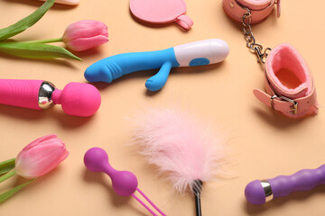 Composition with different sex toys and tulip flowers on beige background, closeup