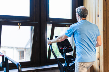 A man is exercising on a stationary bike in front of a window