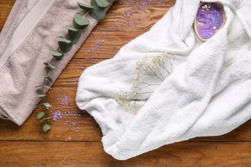 White soft bathrobe with sea salt, eucalyptus and gypsophila flowers on wooden background