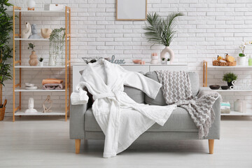White soft bathrobe on sofa in living room
