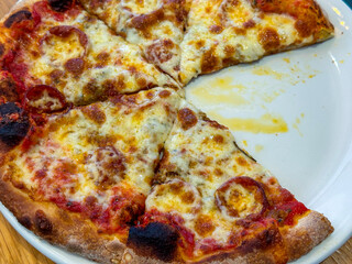 Pepperoni pizza with one slice missing on a white plate