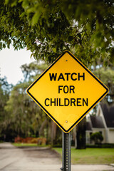 WATCH FOR CHILDREN surrounded by trees on a cloudy day in the USA