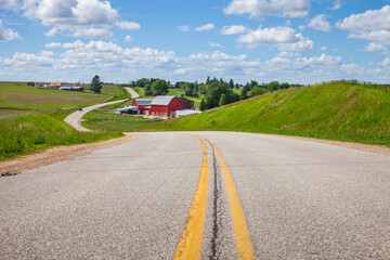 Farm with a red barn on a curving road in the Iowa countryside on a bright spring day