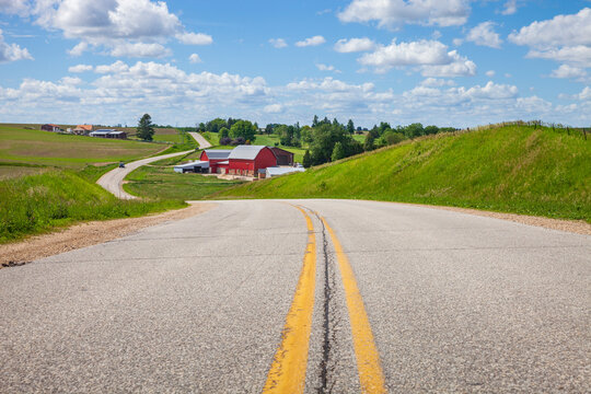 Farm with a red barn on a curving road in the Iowa countryside on a bright spring day