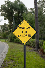 Close-up, crooked, WATCH FOR CHILDREN yellow, diamond sign with space on the left side and tree-lined road and fence in the background, verticle.