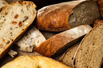 Bread of different varieties cut into pieces. A loaf of dark bread and white bread with nuts and raisins on canvas fabric.