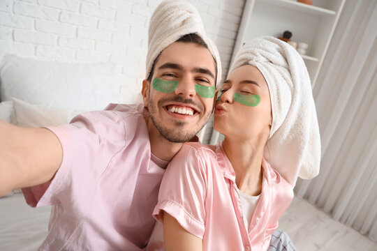 Young loving couple with under-eye patches taking selfie in bedroom, closeup - Powered by Adobe