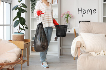 Woman with garbage bag and trash bin at home