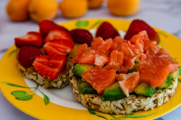 Delicious salmon avocado sandwich on plate, strawberry fruit background, closeup