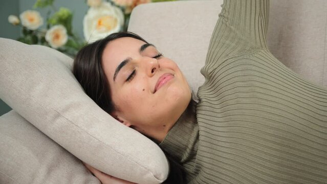 Yawn of a female napping at living room couch, having a good dream then she have a happy wake up . Sleeping young adult woman taking nap on the sofa during the day. Paceful lady taking a siesta