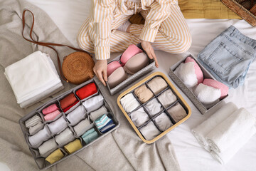 Woman with different clean clothes sitting on bed