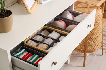 Organizers with clean clothes in open drawer at home