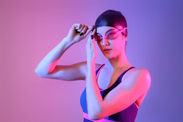 Young female swimmer on color background