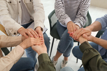 People holding hands at group therapy session, closeup