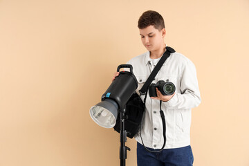 Teenage photographer with professional equipment on beige background