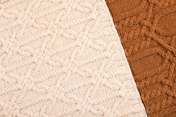 Knitted brown and beige background. Large knitted fabric with a pattern. Close-up of a knitted blanket.