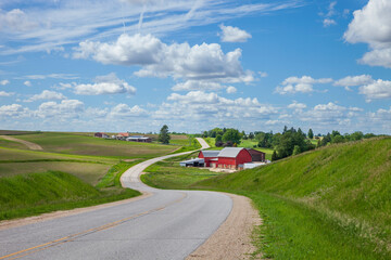 Farm with a red barn on a curving road in the Iowa countryside on a beautiful spring day