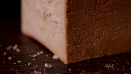 Closeup shot capturing the process of slicing cheese with crumbs visible nearby