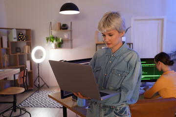 Female programmer working with laptop in office at night